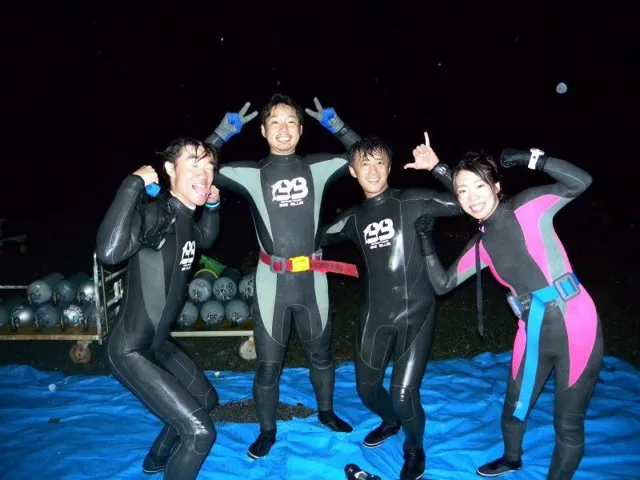 夜の海辺でウェットスーツ姿で並ぶ参加者（2012-2013年）