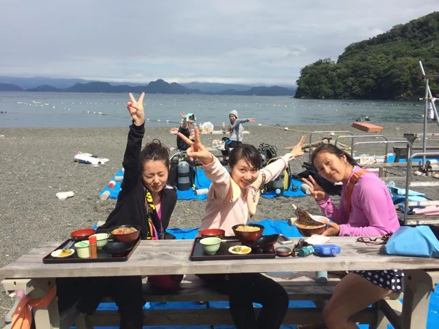 海辺のテーブルで食事を囲む参加者（2015年）