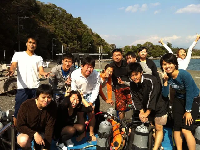 伊豆・大瀬崎でのダイビング:海辺で器材と並ぶ参加者