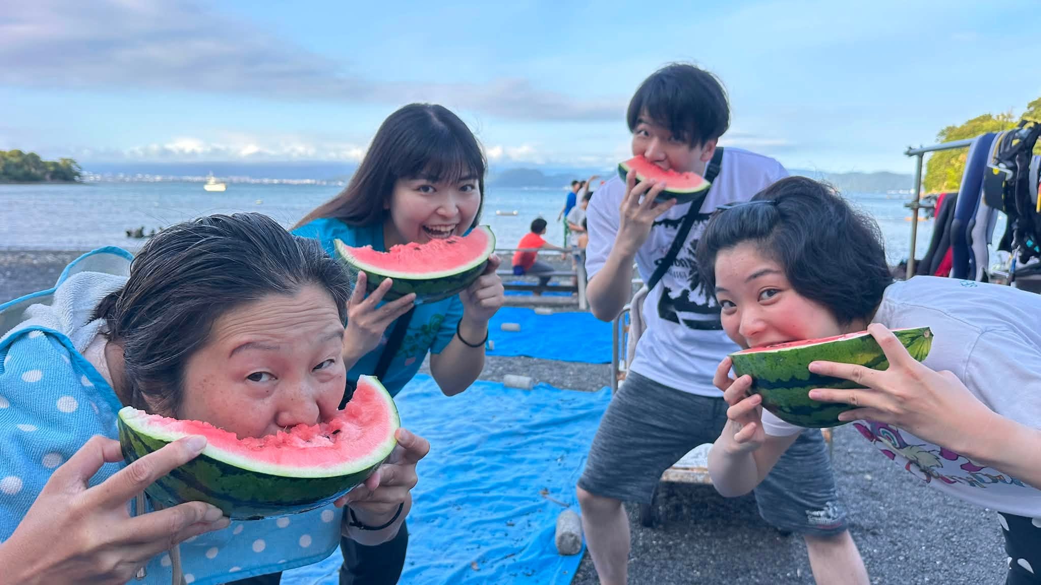 2026年7月26日(投稿日) / 海辺でスイカを食べる4人の参加者
