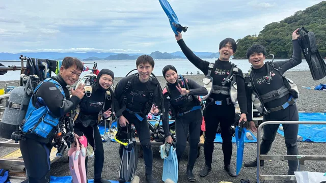 海辺でウェットスーツ姿で並ぶダイビングの参加者