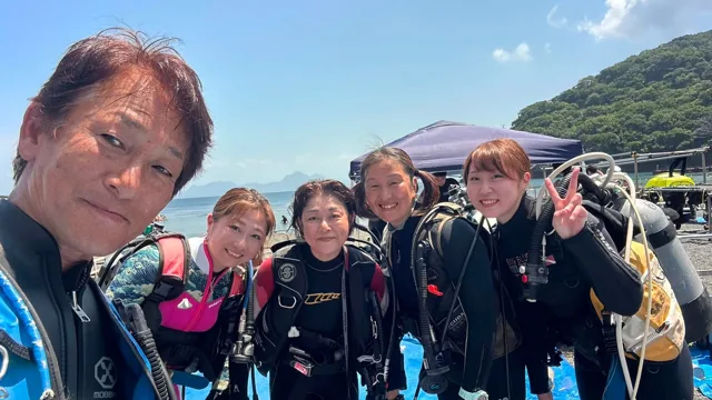 海辺で記念撮影する5人の参加者