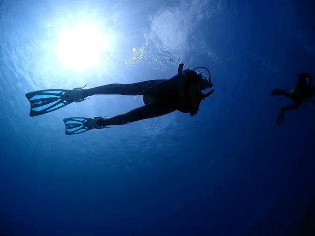 伊良部島での青い光が差す水中を泳ぐダイバー