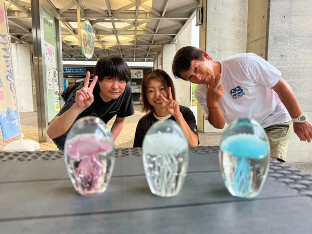 旅先で記念品を前に撮影する3人の参加者