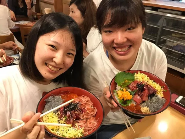 海のツアーの食事で海鮮丼を楽しむ2人の参加者(元アルバムから推定)