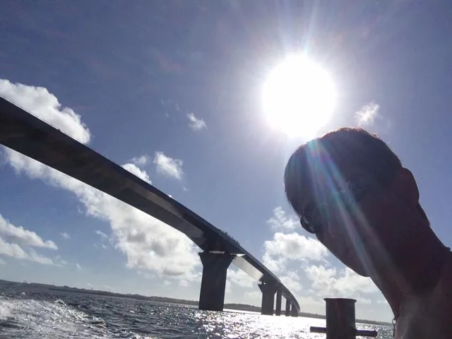 沖縄県・宮古島での宮古島ツアーのボートで青空と太陽を背景に撮影する参加者
