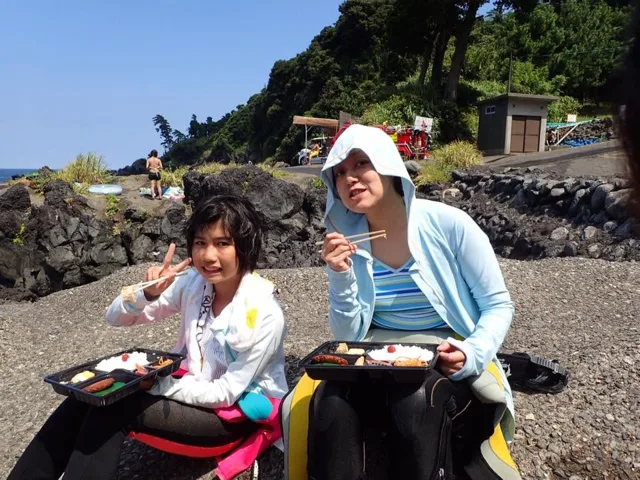伊豆大島（元アルバムによる）での大島ツアーの海辺でお弁当を楽しむ2人の参加者