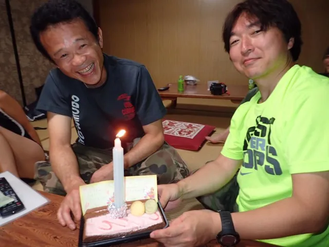 伊豆大島（元アルバムから推定）でのダイビング：大島ツアー中、ケーキを前に誕生日を祝う2人の参加者