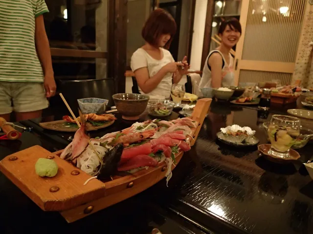 食事場所未確認でのダイビングライセンス講習の元アルバムにある舟盛りを囲む食事風景。店名と場所は未確認