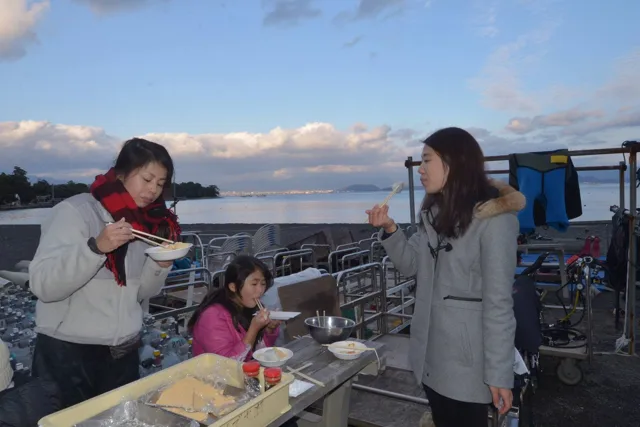 伊豆・大瀬崎でのダイビング：大瀬崎の海辺で餅を味わう参加者たち