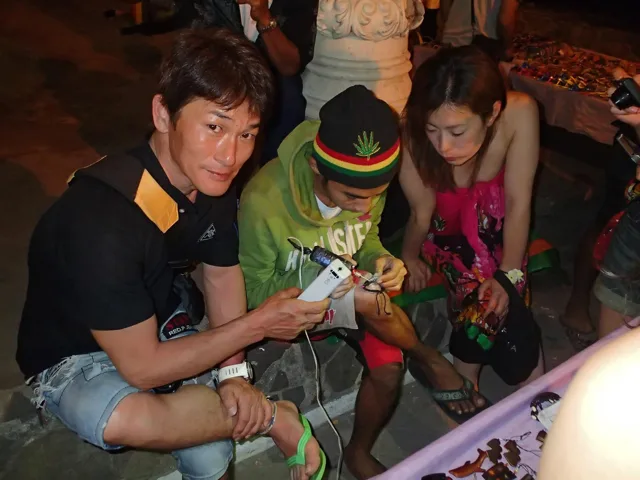 フィリピン（アポ島・スミロン島・ドゥマゲッティ方面、地点未確認）でのフィリピンダイビングツアーの夜に現地の人と写真を撮る参加者