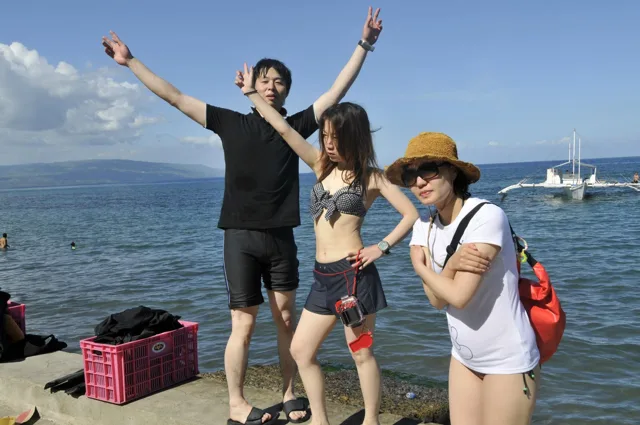 フィリピン（アポ島・スミロン島・ドゥマゲッティ方面、地点未確認）でのフィリピンダイビングツアーの海辺で手を広げる参加者たち