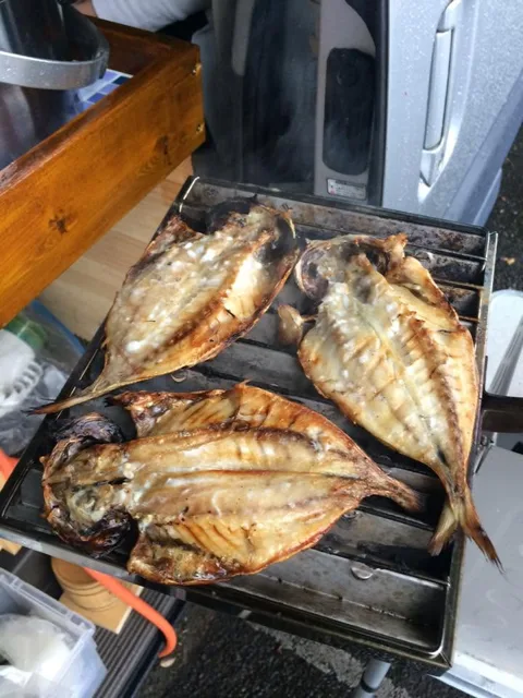 車の脇の焼き網で調理した魚の干物